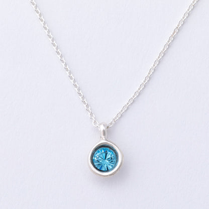 Silver necklace with a blue gemstone pendant on a light gray background