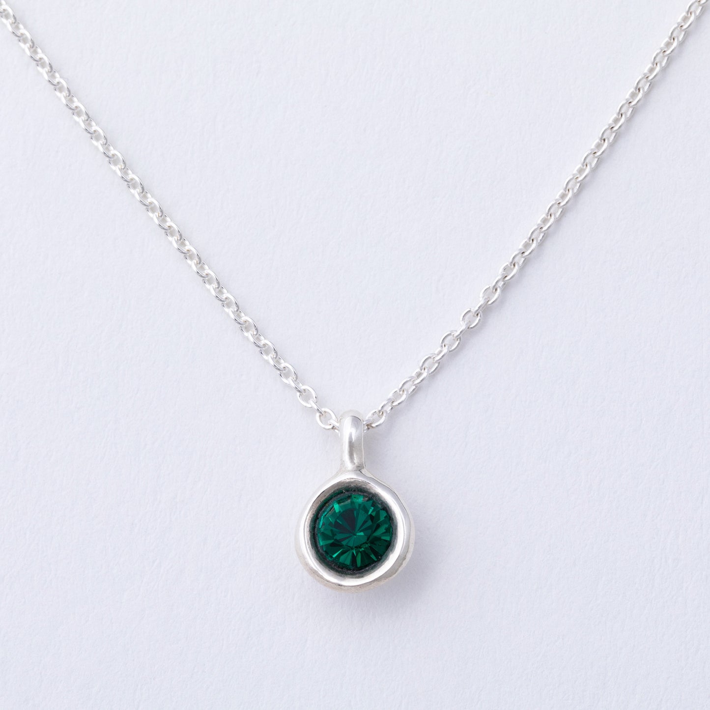 Silver necklace with a green gemstone pendant on a light gray background