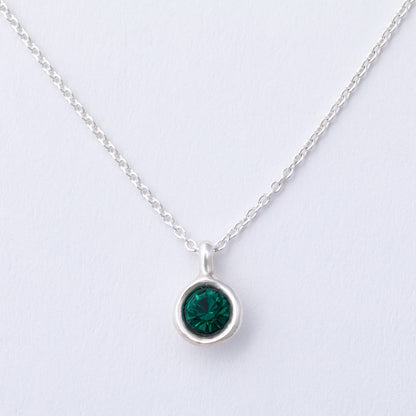 Silver necklace with a green gemstone pendant on a light gray background