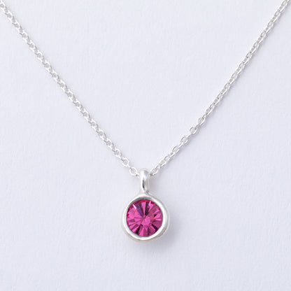 Silver necklace with a pink gemstone on a light gray background
