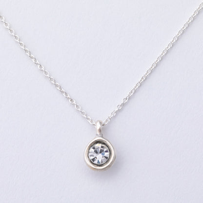Silver necklace with a round pendant on a light gray background