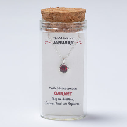 Glass jar with a necklace inside, featuring a message and birthstone information.