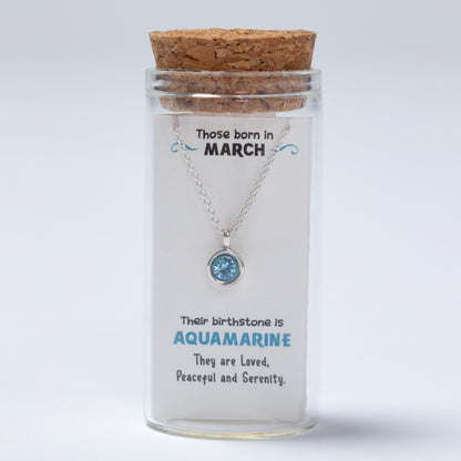 Necklace in a glass jar with a cork lid, featuring information about March birthstones on a white background.