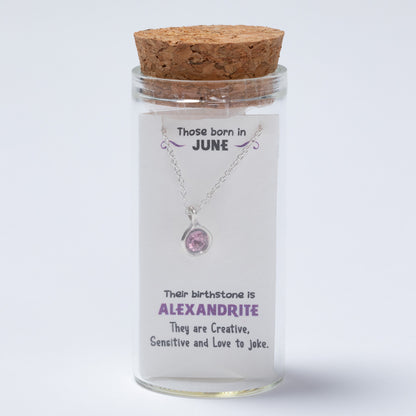 Necklace in a glass jar with cork lid on a white background