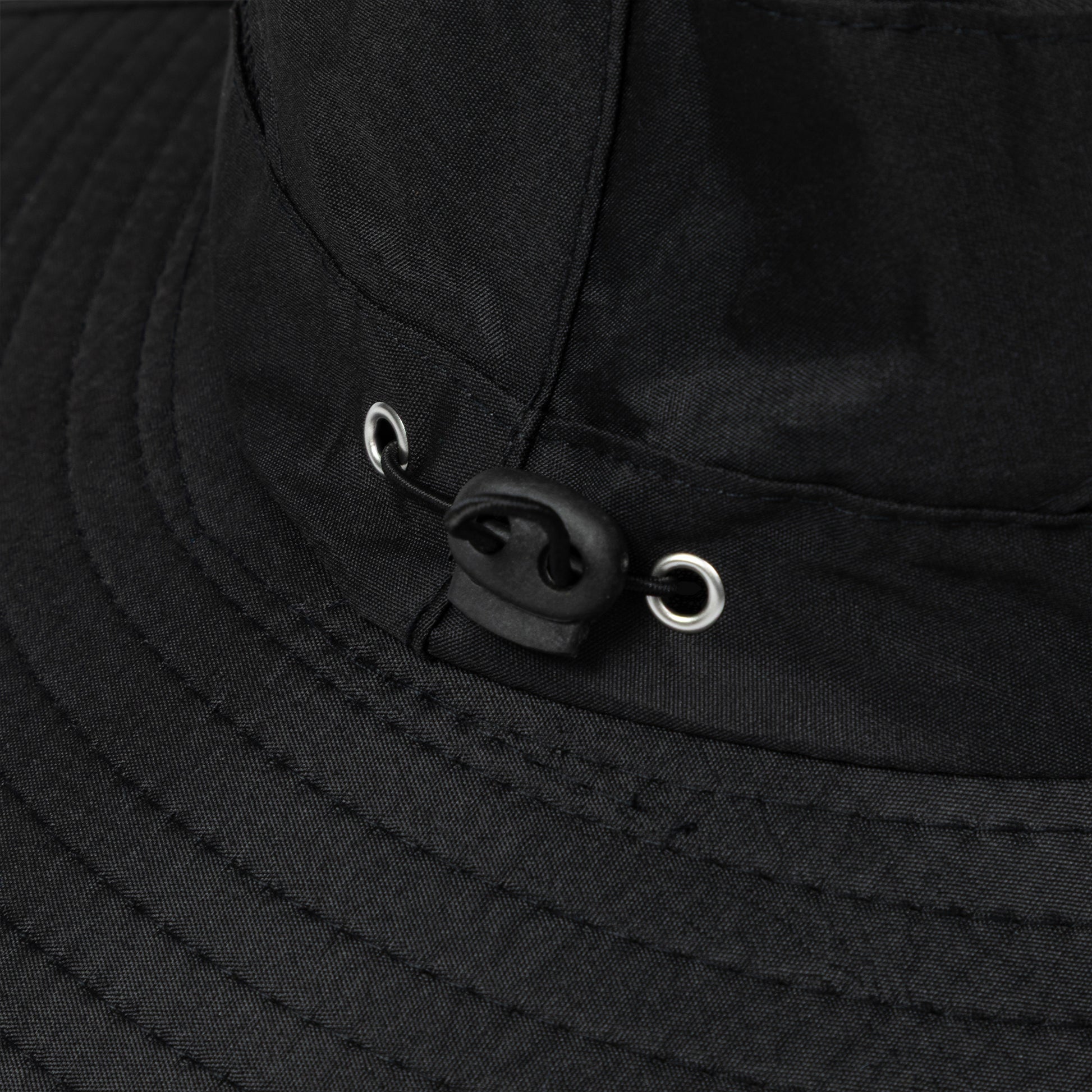 Close-up of a black sun hat with a toggle for adjusting the fit.