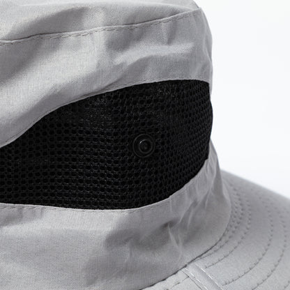 Close-up of a gray bucket hat with a black vented side and button on a white background