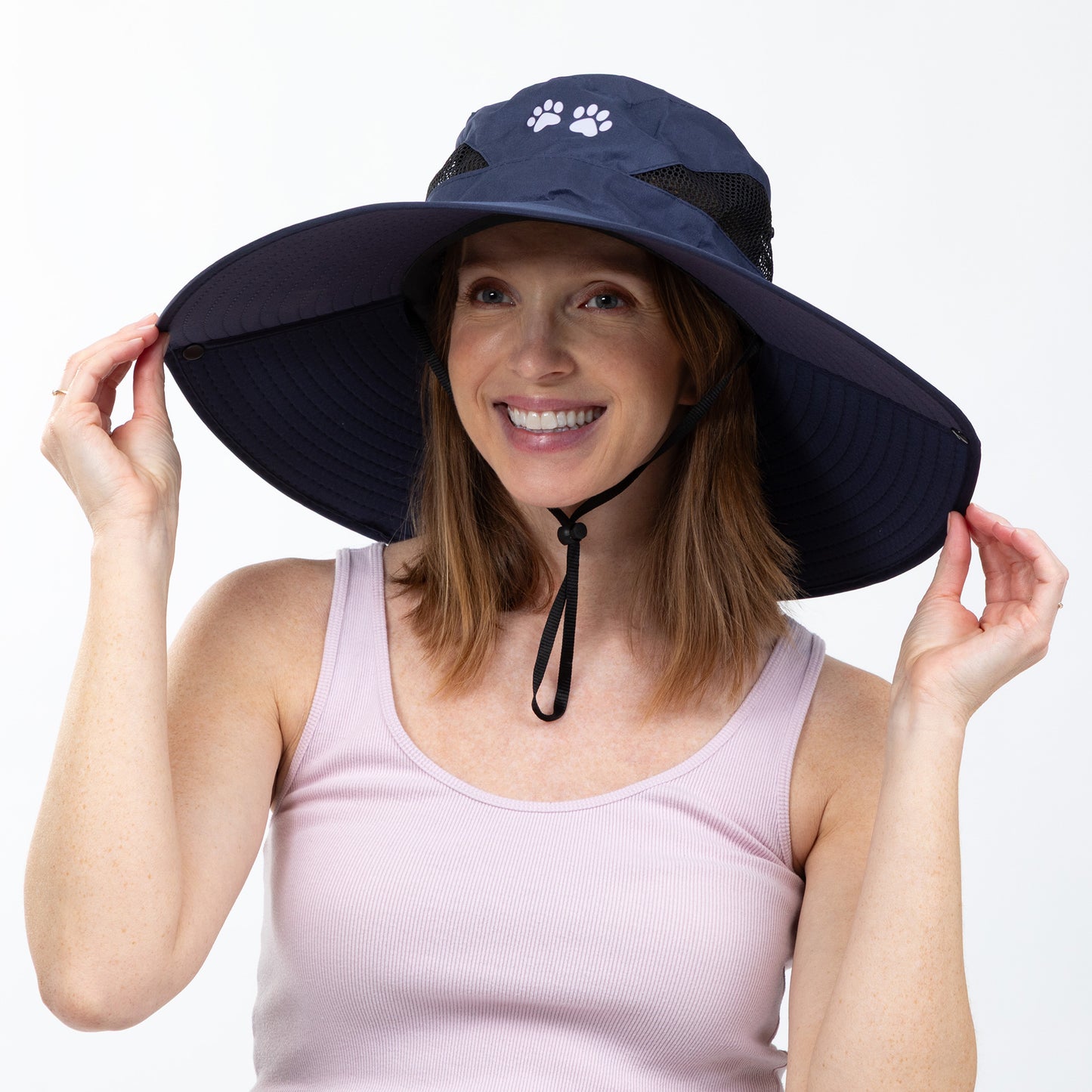 Woman wearing a navy blue sun hat with a paw print design on a white background