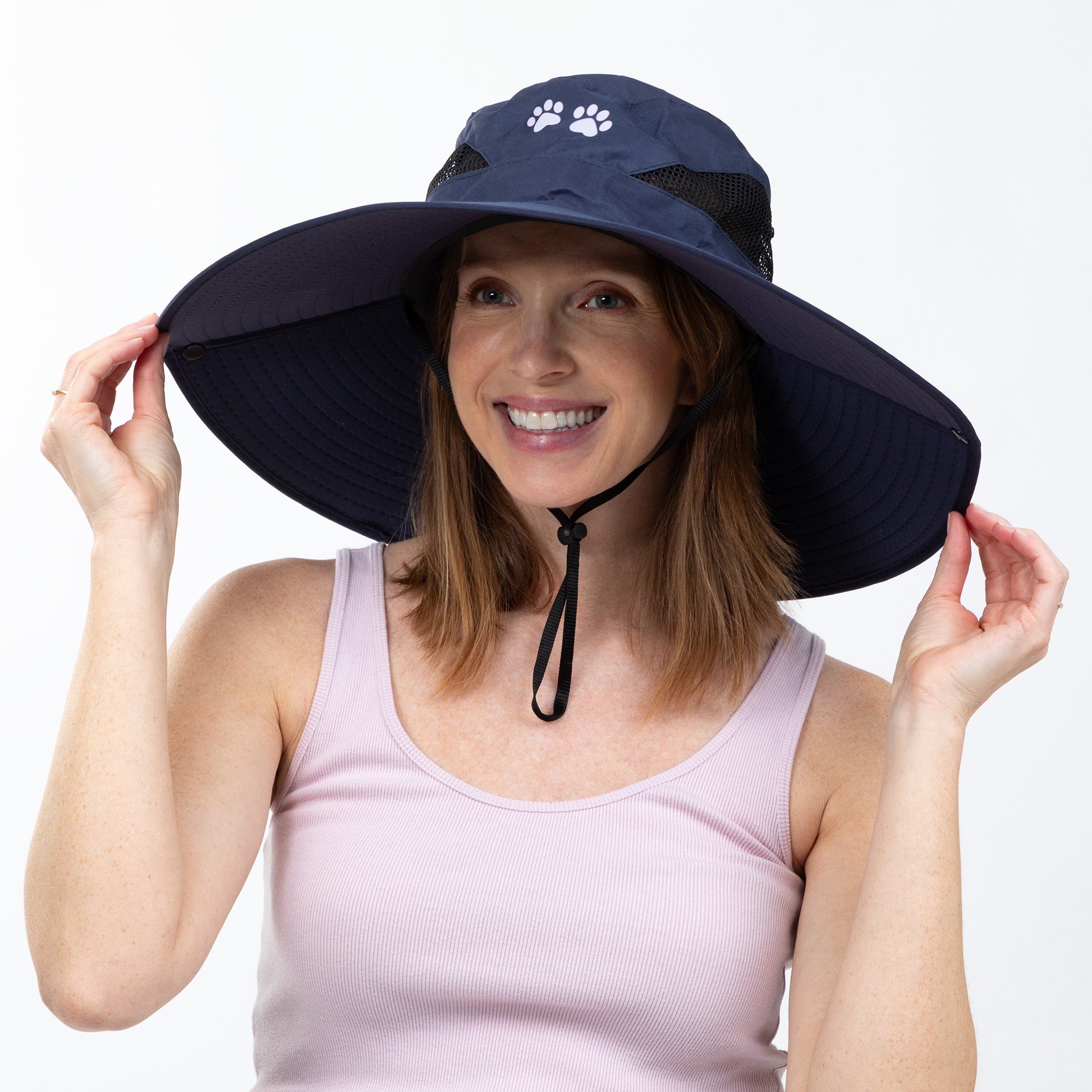 Woman wearing a navy blue sun hat with a paw print design on a white background