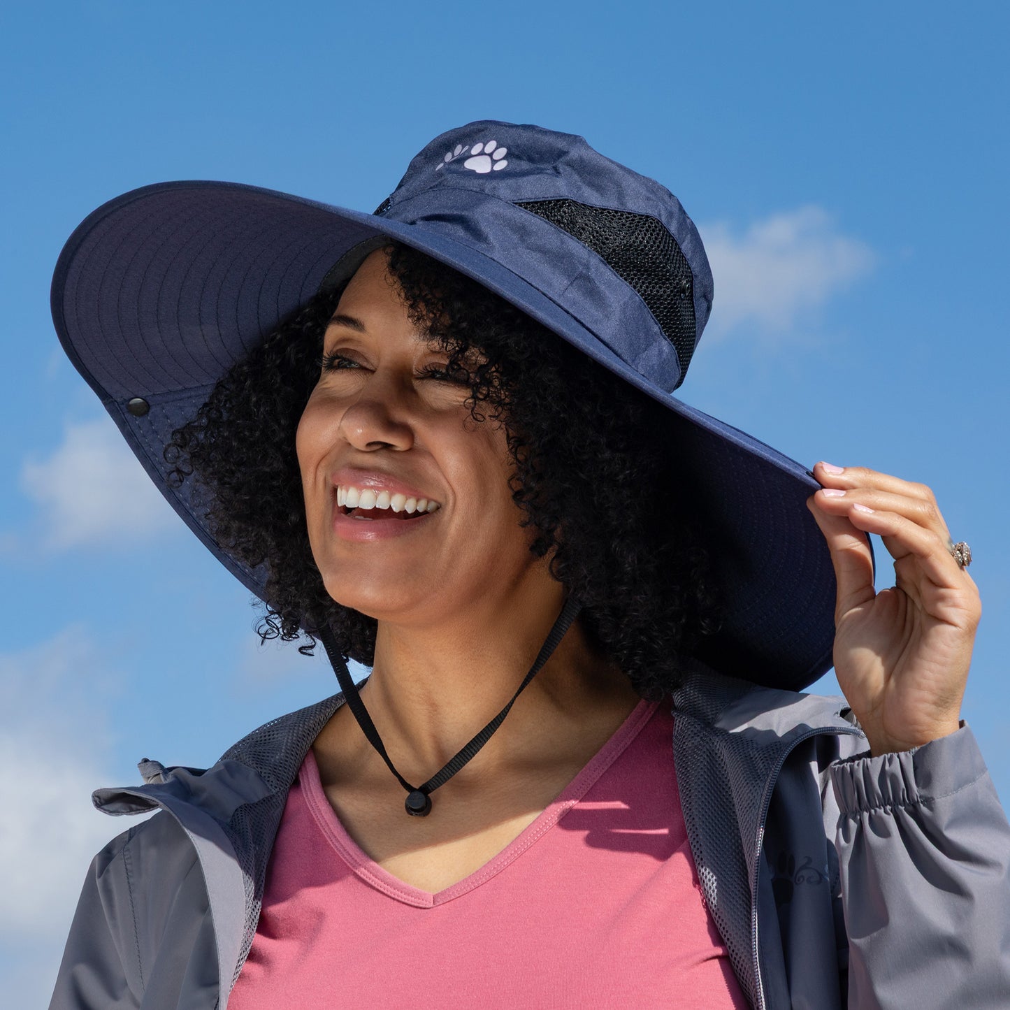 Woman wearing a wide-brimmed navy hat against a blue sky.