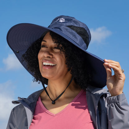Woman wearing a wide-brimmed navy hat against a blue sky.