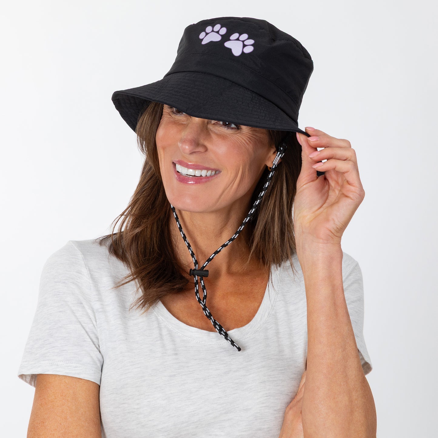 Woman wearing a black bucket hat with a paw print design on a white background