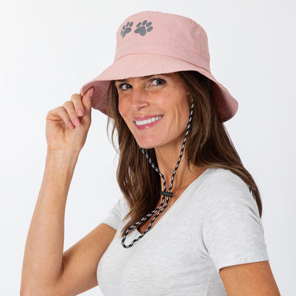 Woman wearing a pink bucket hat with paw prints on a white background