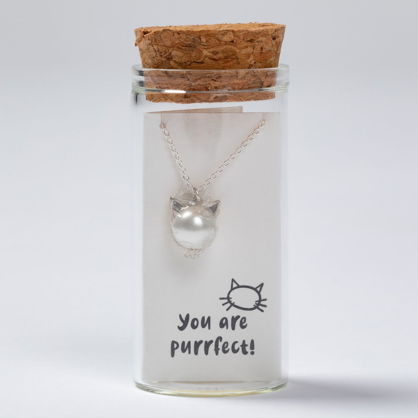 Cat-shaped necklace in a glass jar with a cork lid on a white background