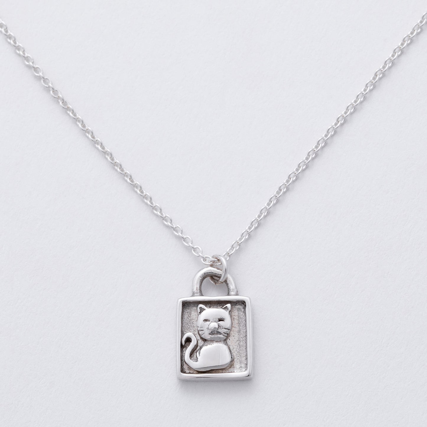 Silver necklace with a cat pendant on a light gray background
