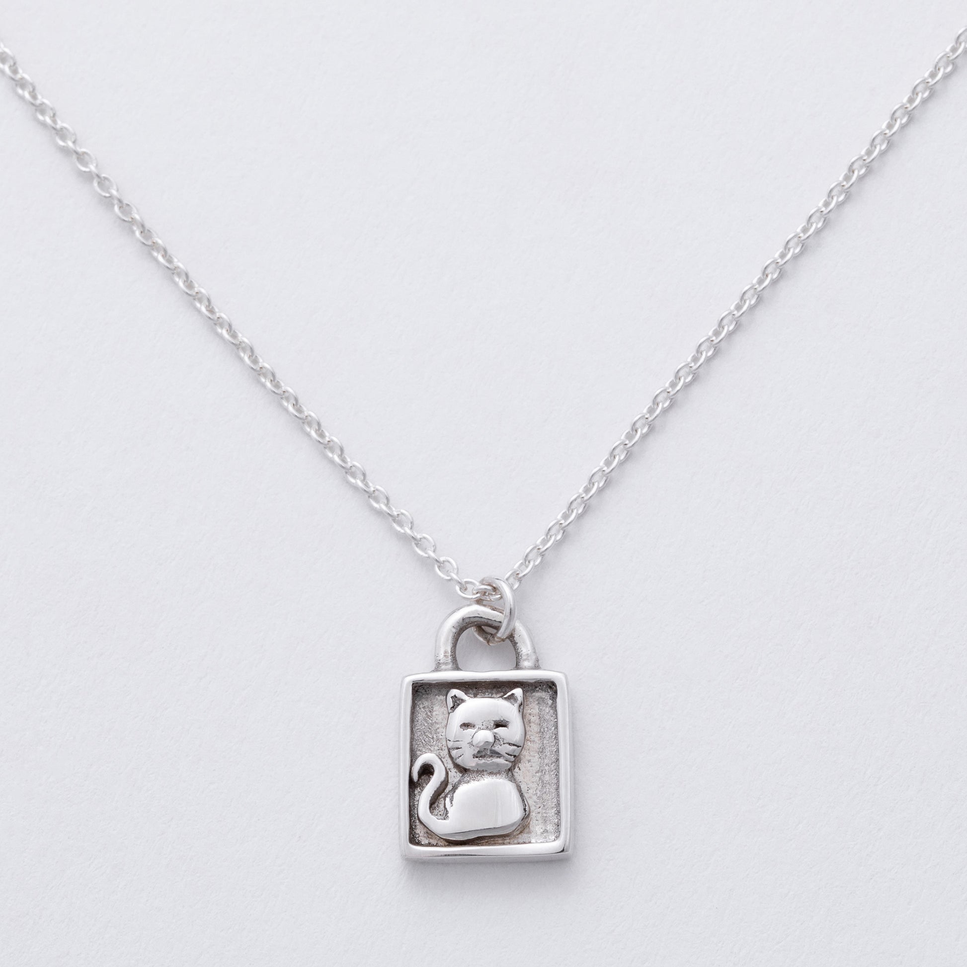 Silver necklace with a cat pendant on a light gray background