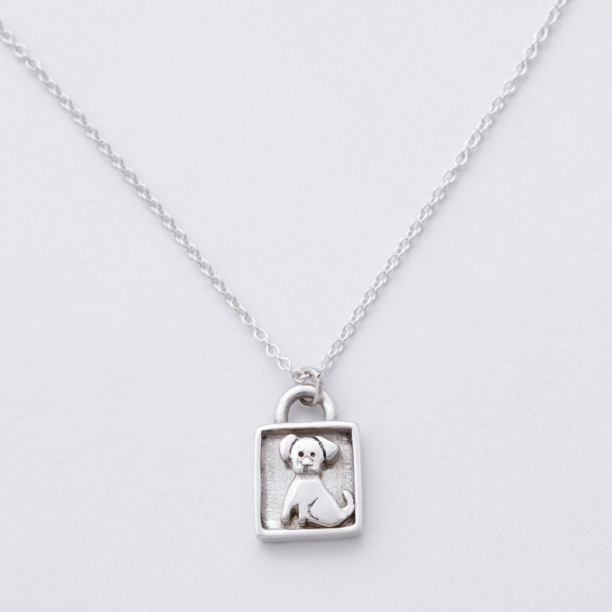 Silver necklace with a pendant featuring a dog design on a light gray background
