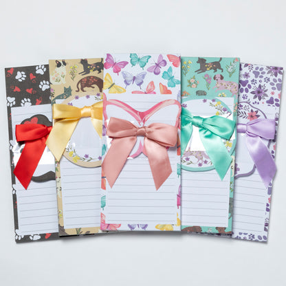 Set of five colorful notepads with decorative designs and ribbons on a white background