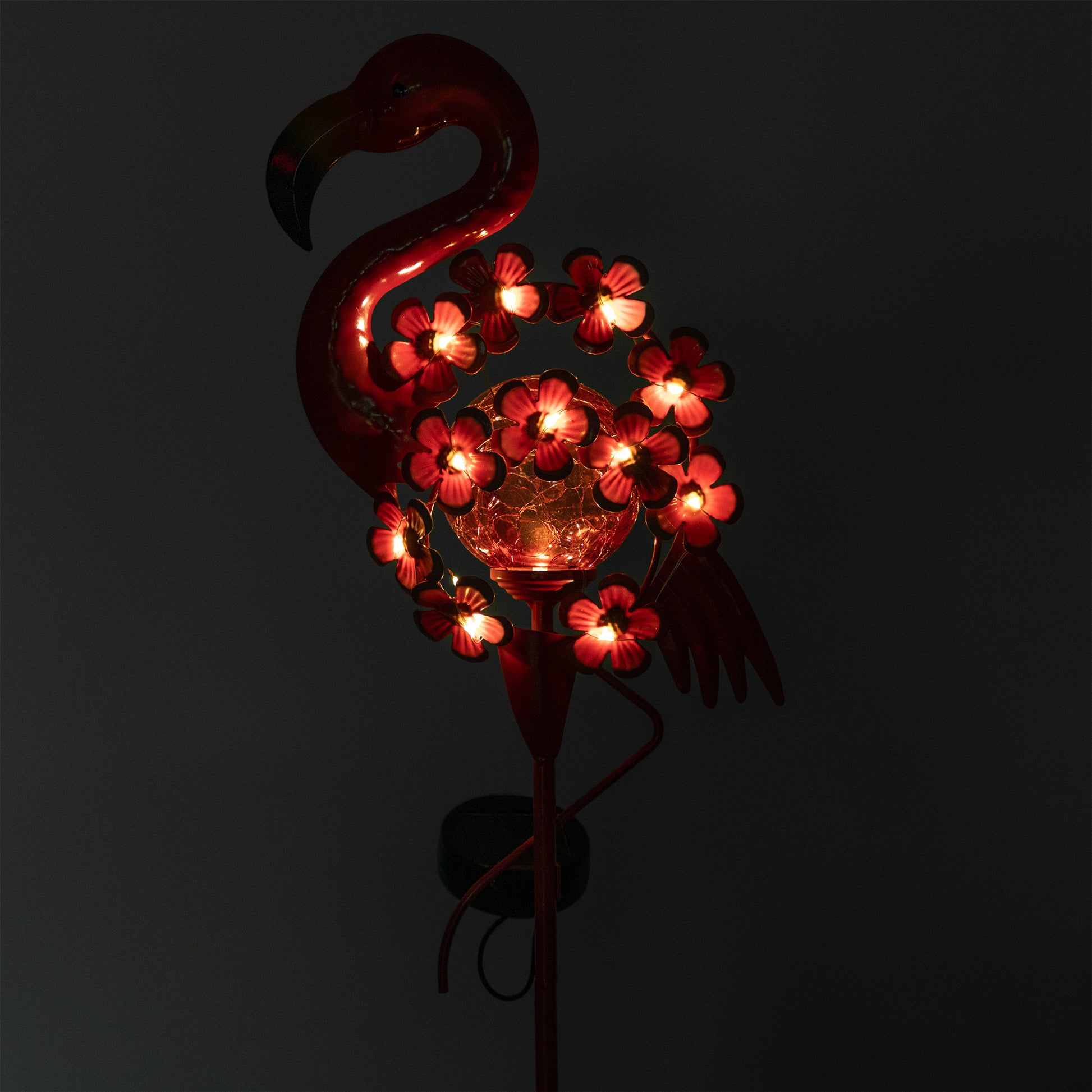Flamingo-shaped solar light with glowing flowers on a dark background