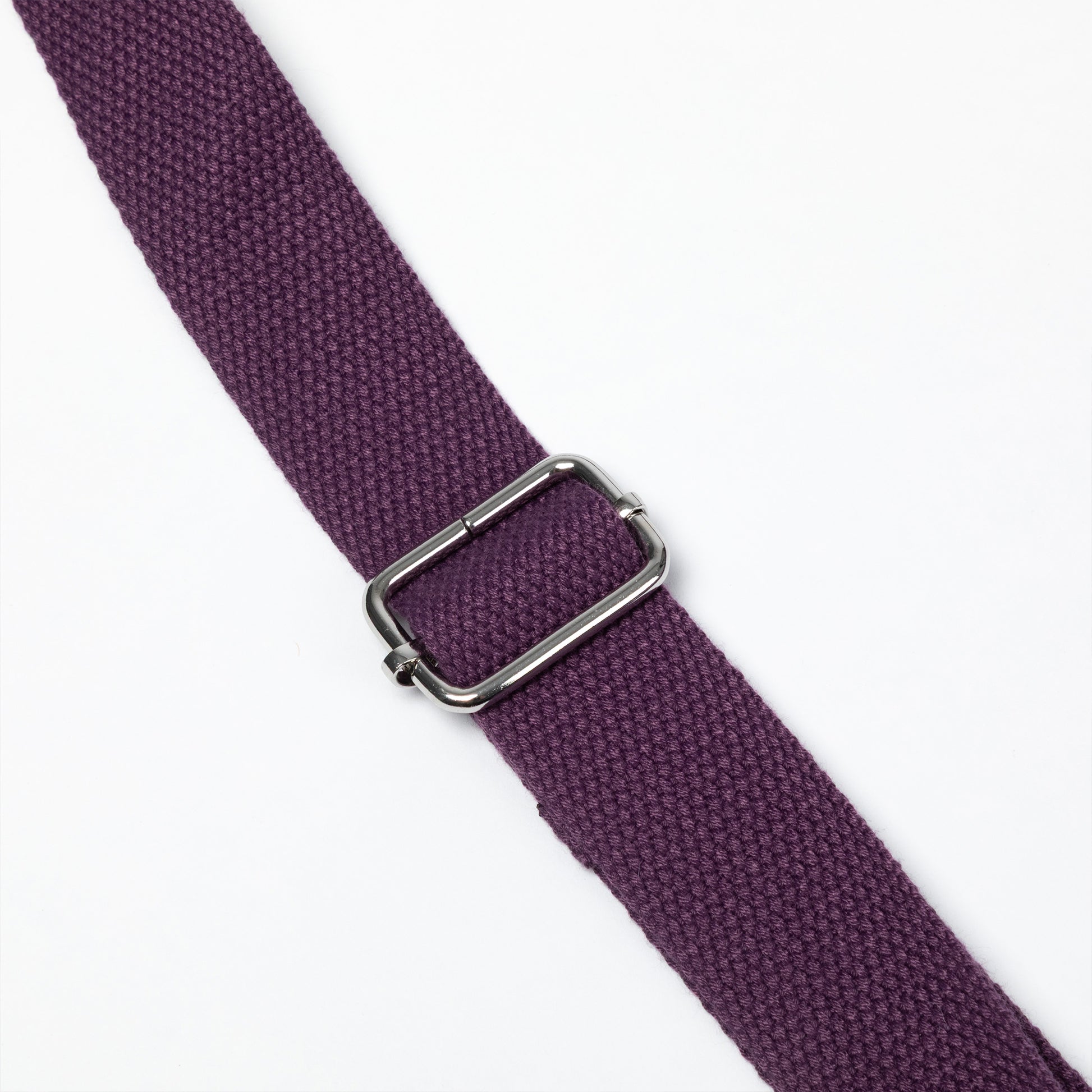 A close-up of a textured purple woven strap with a silver-toned metal buckle, shown diagonally on a plain white background.