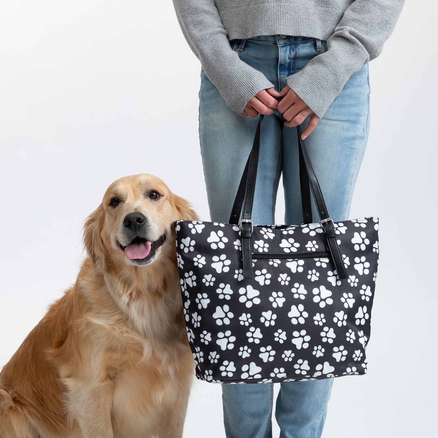 Person holding a dog-themed tote bag beside a golden retriever.
