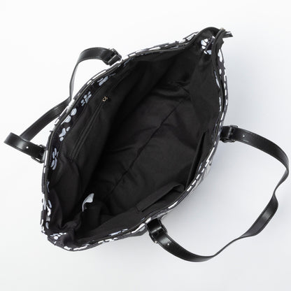 Black tote bag with white paw prints, viewing the interior lining with pockets.