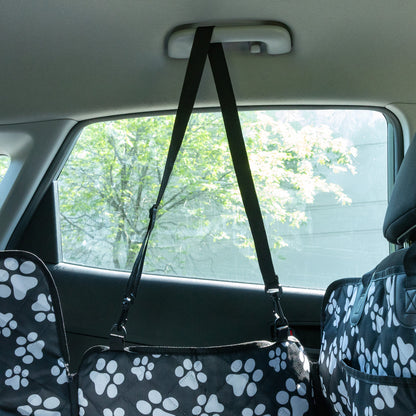 Car interior with a pet seat cover and harness, showing a view of trees outside.