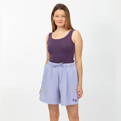 Woman wearing a purple tank top and light purple shorts with paw prints on a white background
