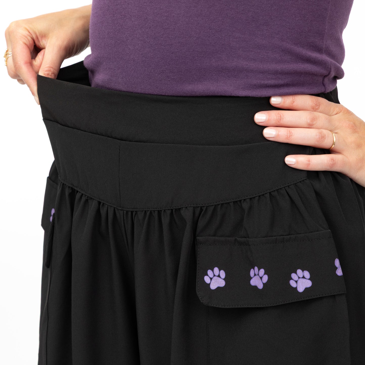 Black shorts with purple paw prints held by a person wearing a purple shirt.