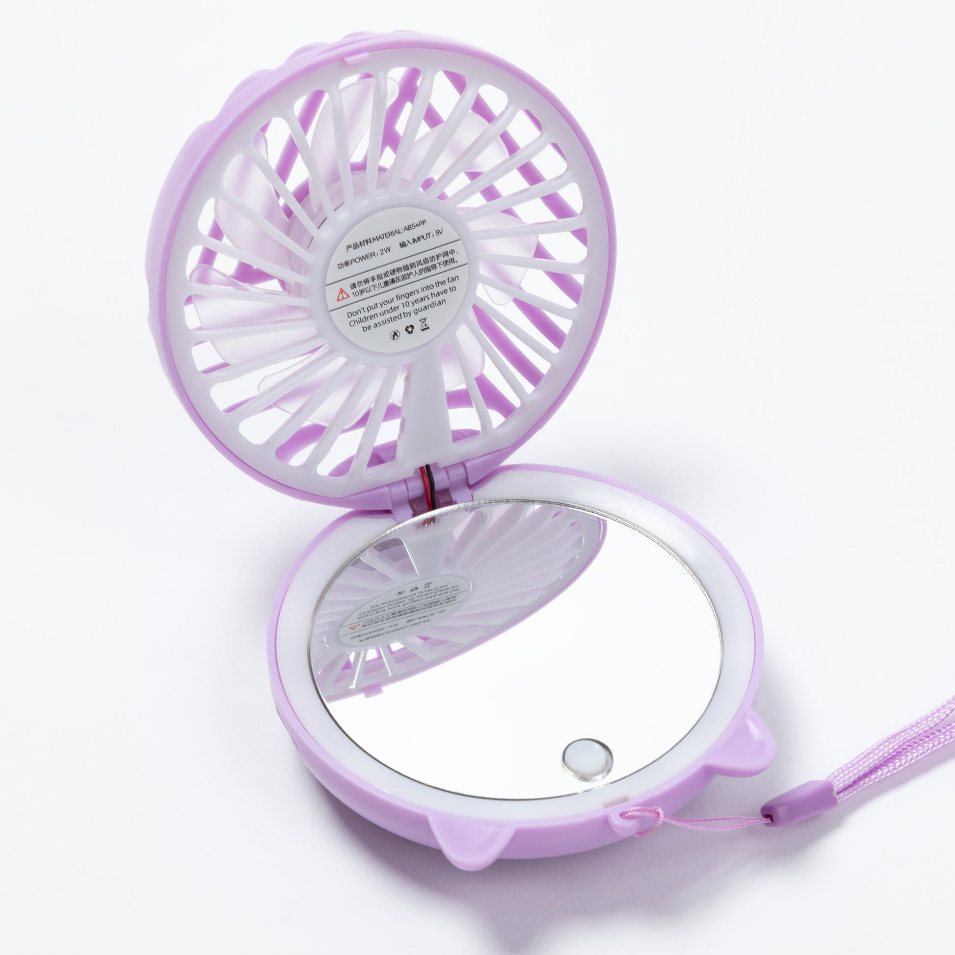 A compact, circular purple handheld fan with an attached mirror on the bottom half, shown open on a white background.
