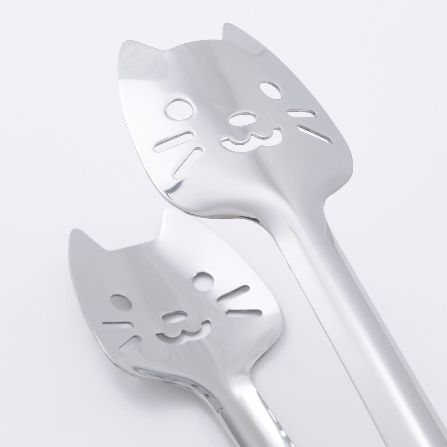 Two cat-shaped utensils on a light gray background