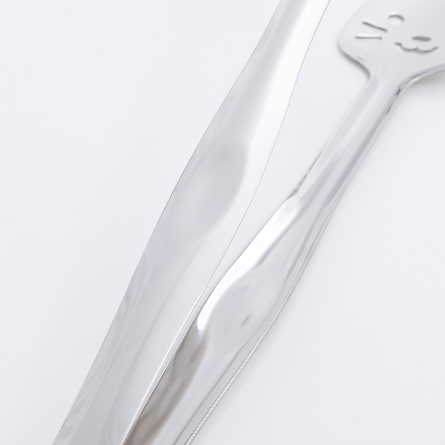 Close-up of a stainless steel tong on a light gray background