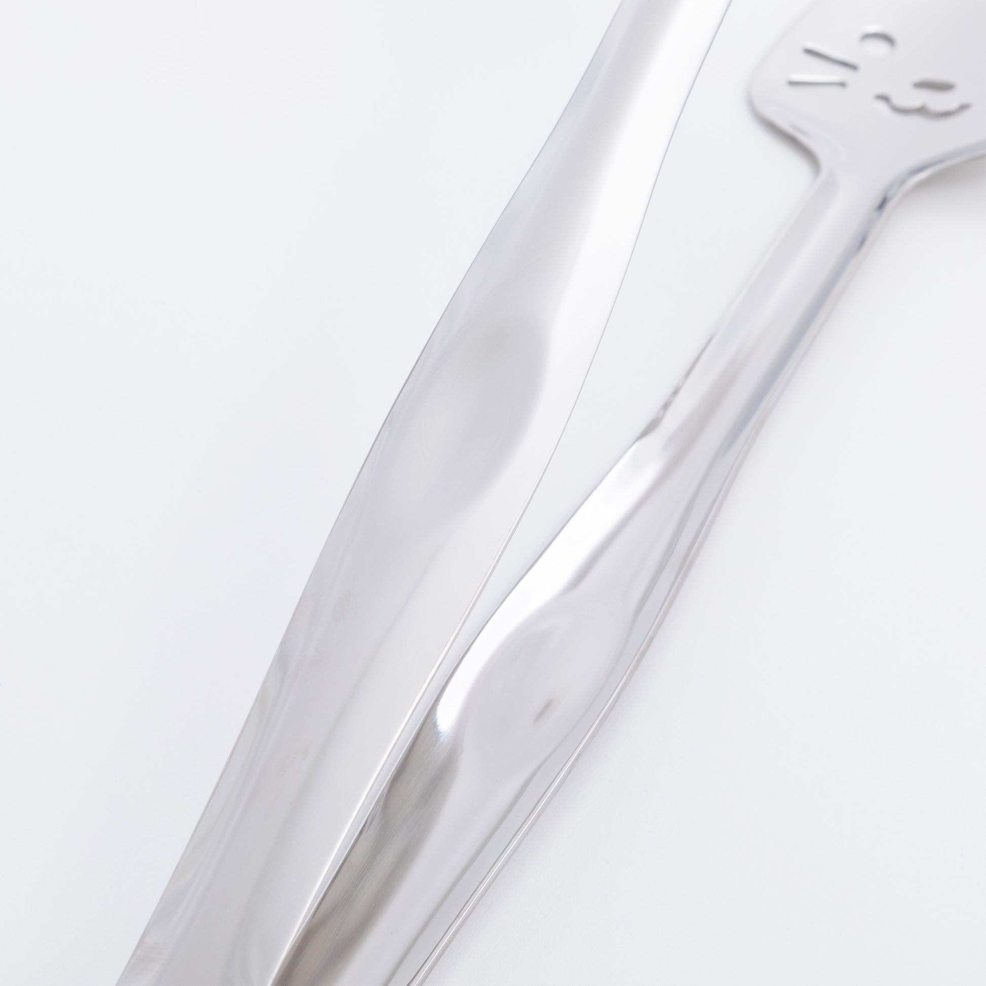 Close-up of a stainless steel tong on a light gray background