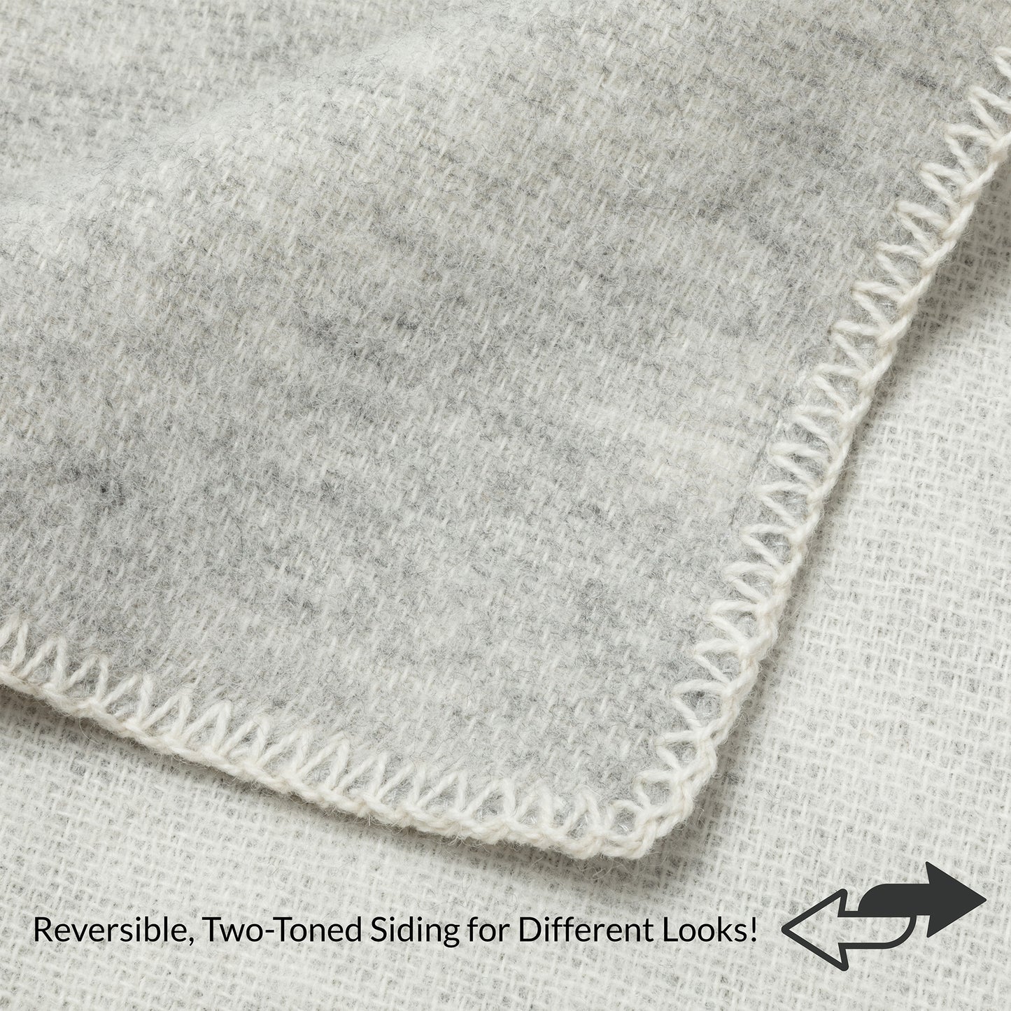 Close-up of a light gray heathered fabric corner with white zigzag stitching, showing reversible two-toned sides with text and arrow overlay.