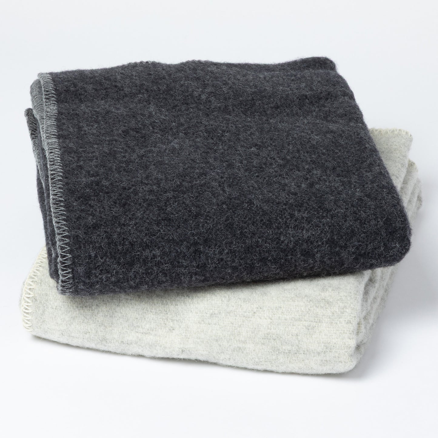 Two folded textured blankets, one dark charcoal gray and one light heather gray, stacked on a white background.