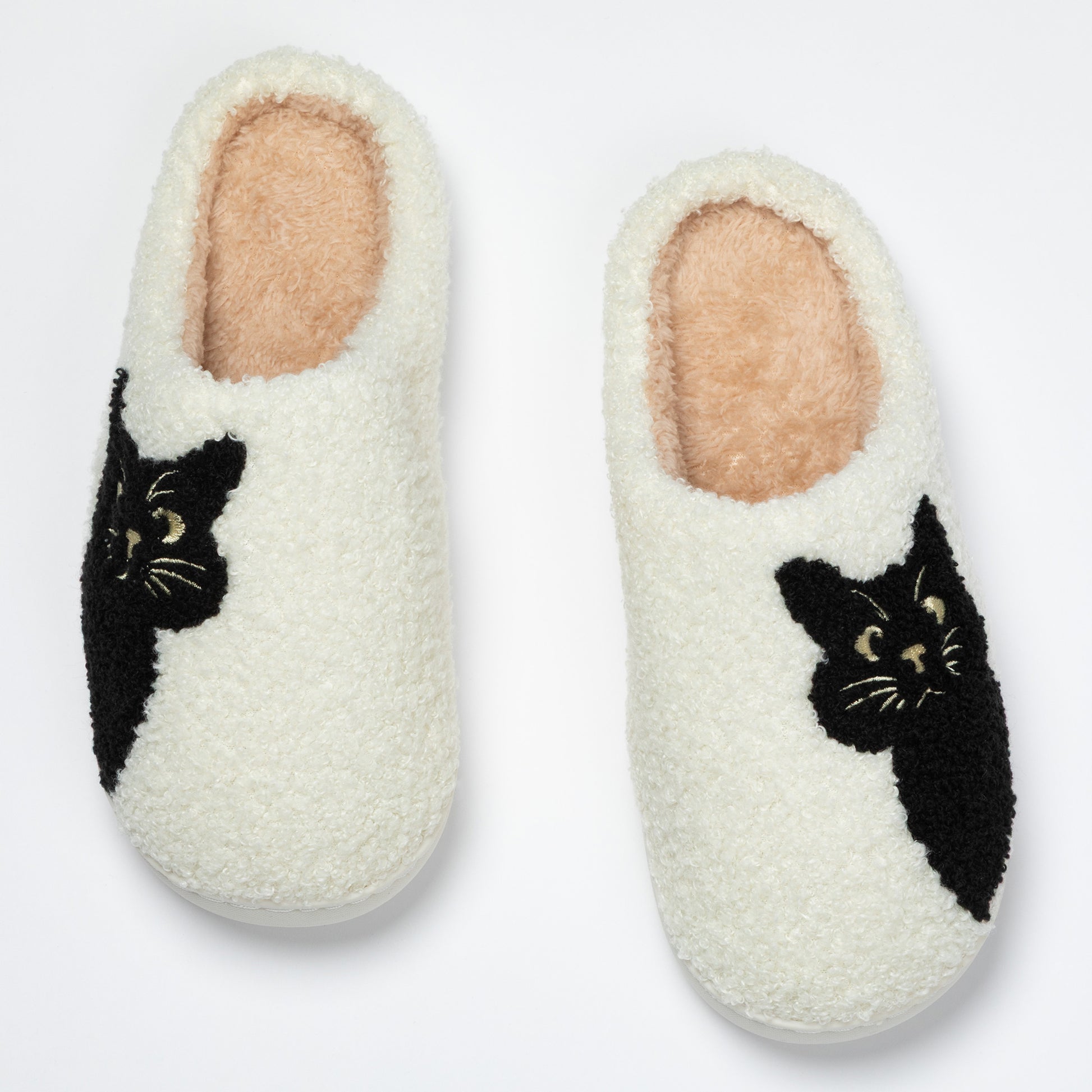 Pair of white slippers with black cat designs on a light gray background