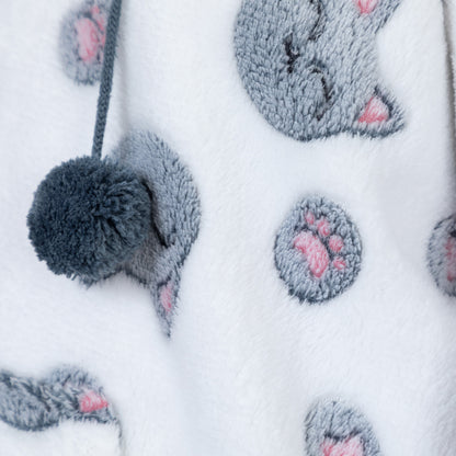 Close-up of a white plush fabric featuring a gray cat face and paw print pattern with pink paw pads, plus a gray pom-pom drawstring.