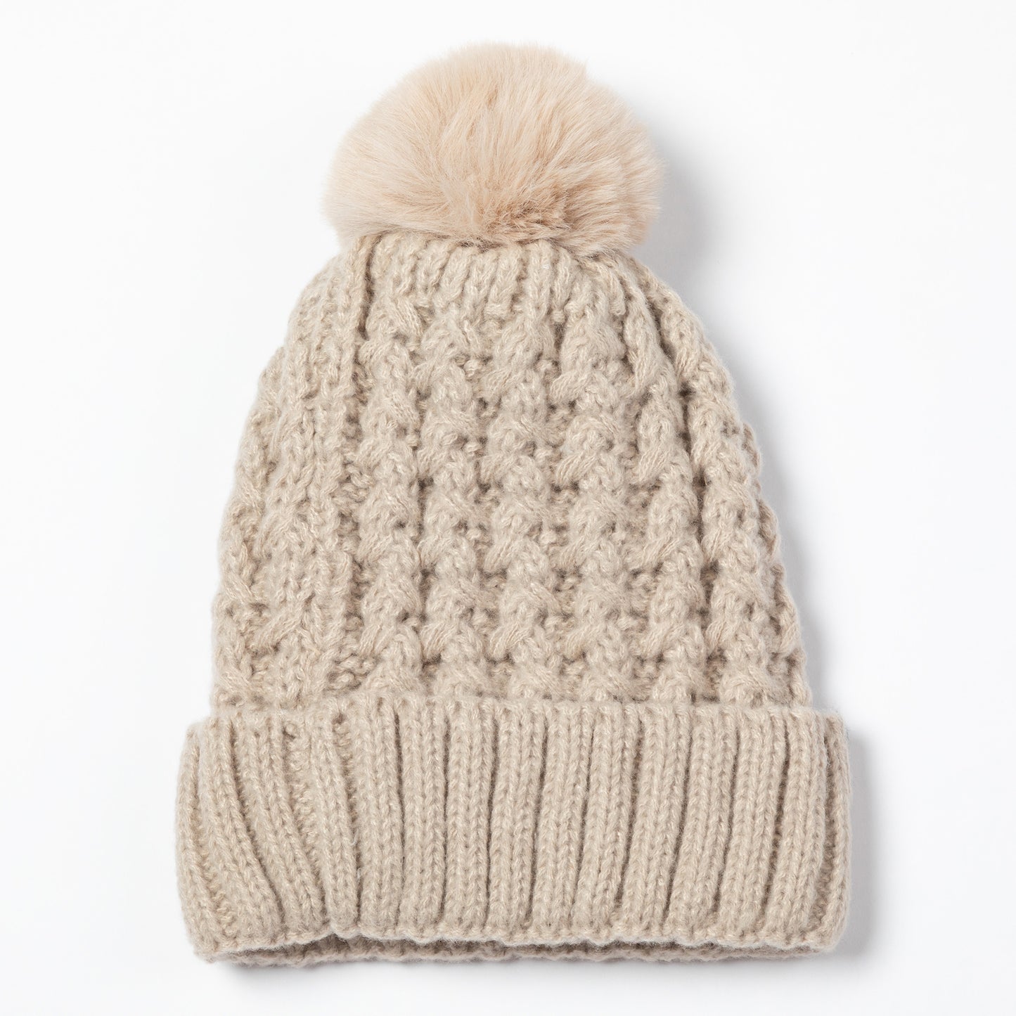 A beige cable-knit beanie hat with a matching faux-fur pom-pom on top, shown against a plain white background.