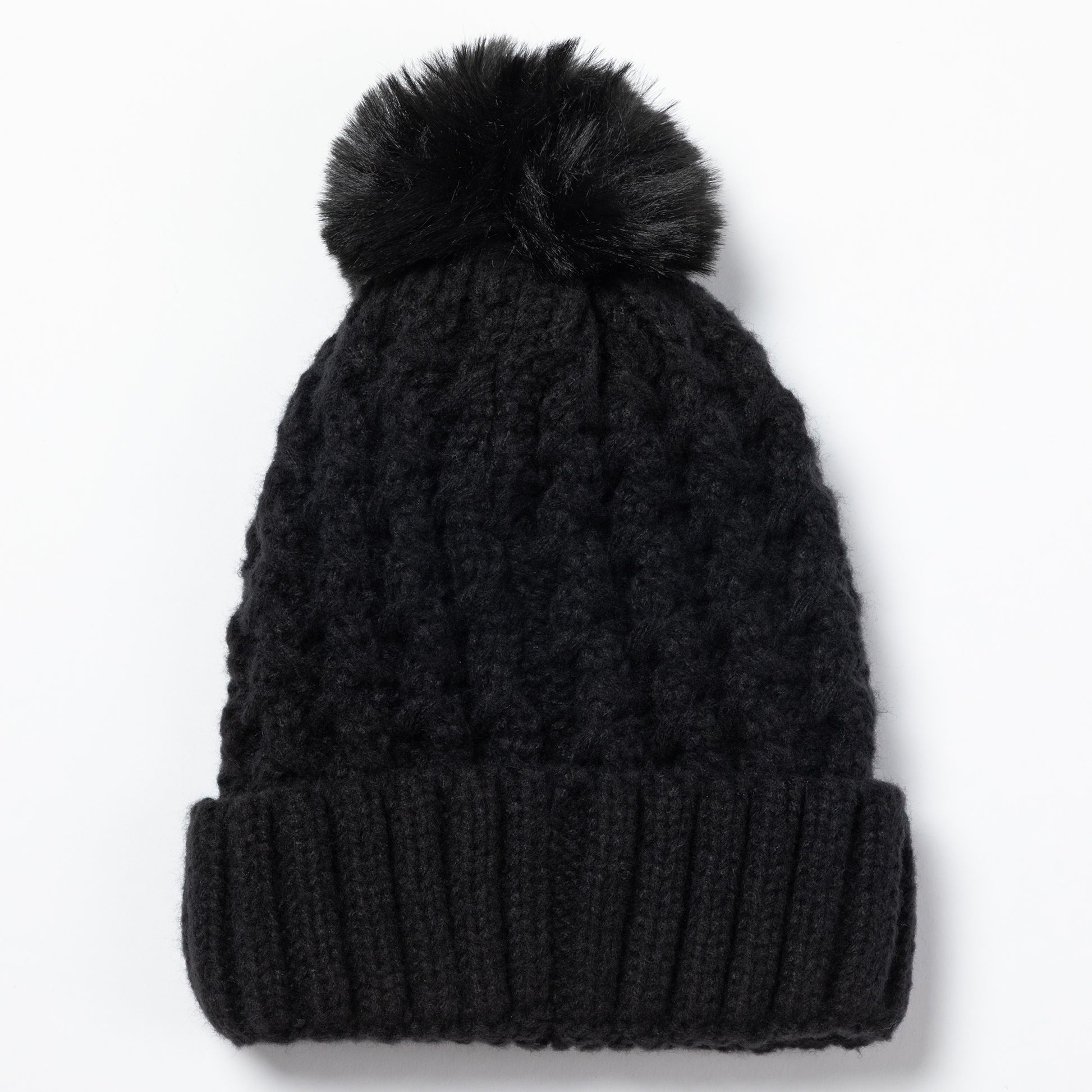 A black cable-knit beanie with a matching black faux fur pom-pom on top, shown against a plain white background.