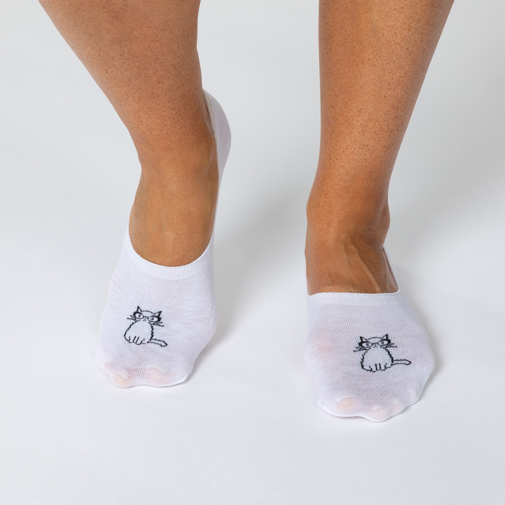 White socks with cat design worn by a person on a light gray background