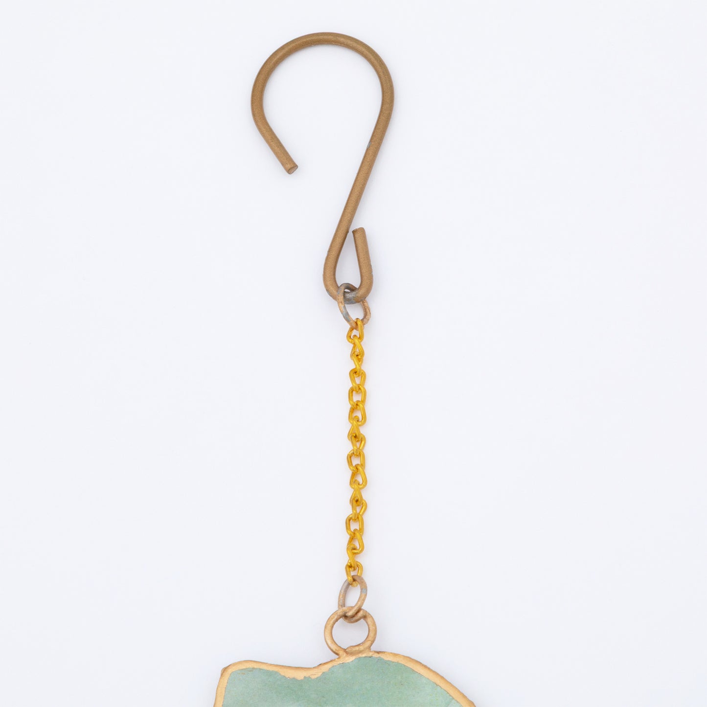 Gold hook hanging a pet shaped wind chime with a white background.