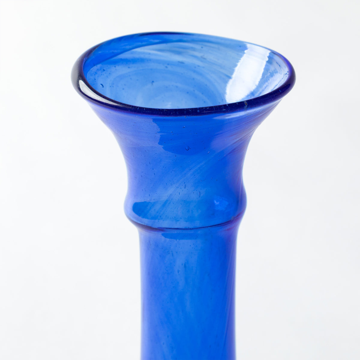 A close-up of a cobalt blue glass vase with a smooth cylindrical body, photographed against a plain white background.