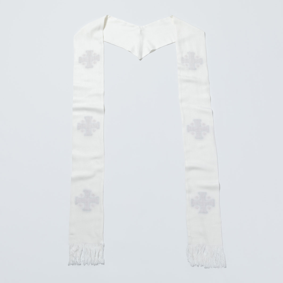 A white woven religious scarf with a V-shaped top and fringe ends, featuring four light gray embroidered crosses on each side, laid flat against a light gray background.