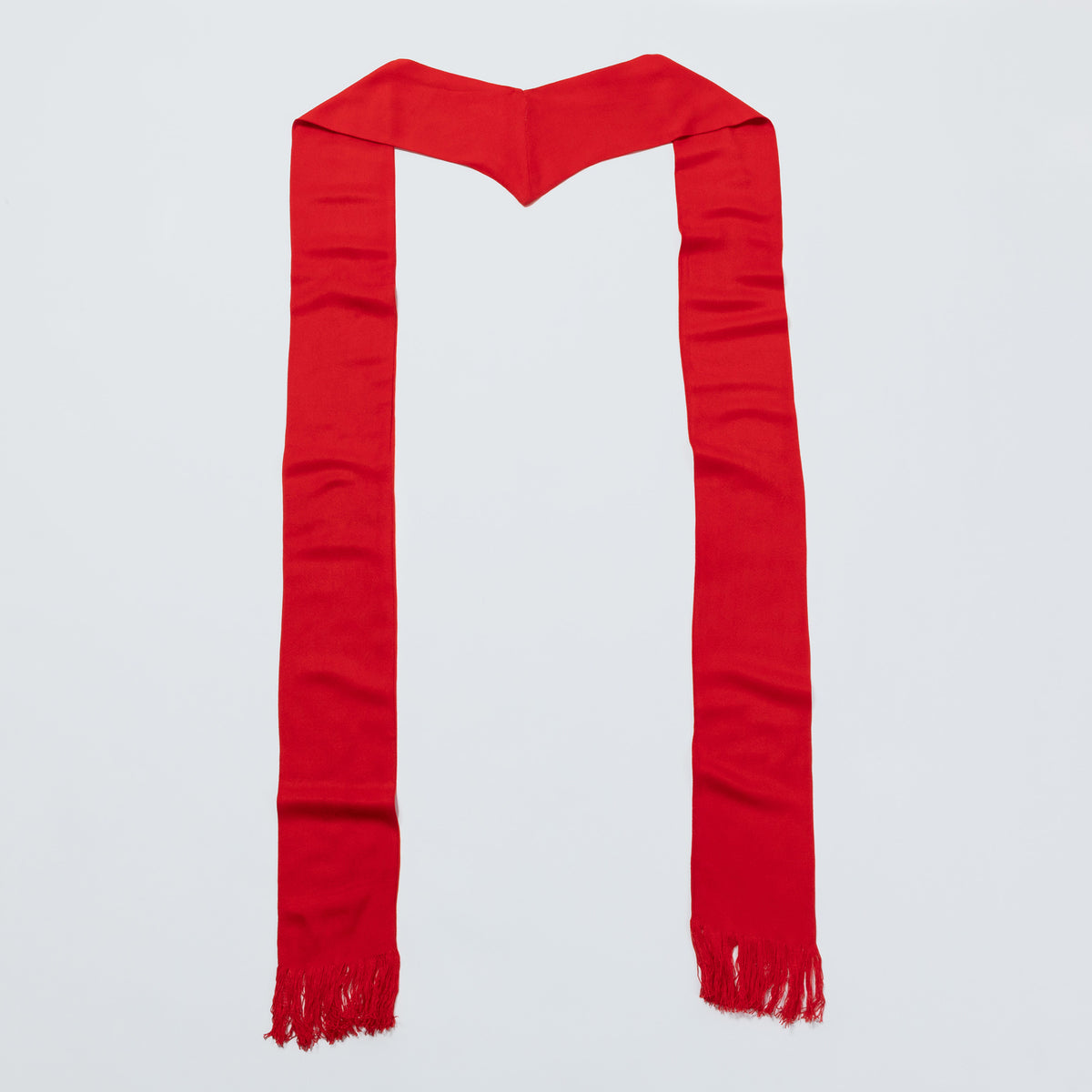 A bright red scarf with fringed ends, laid flat in a U-shape against a light gray background.