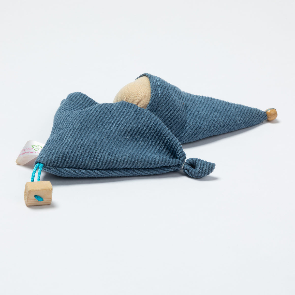 A blue ribbed fabric doll with a wooden pom-pom on the tip of the hat, a wooden pom-pom on the bottom corner, and a small white tag attached.