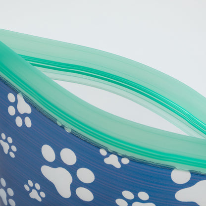 Blue reusable bag with white paw prints and green zipper top on a light gray background