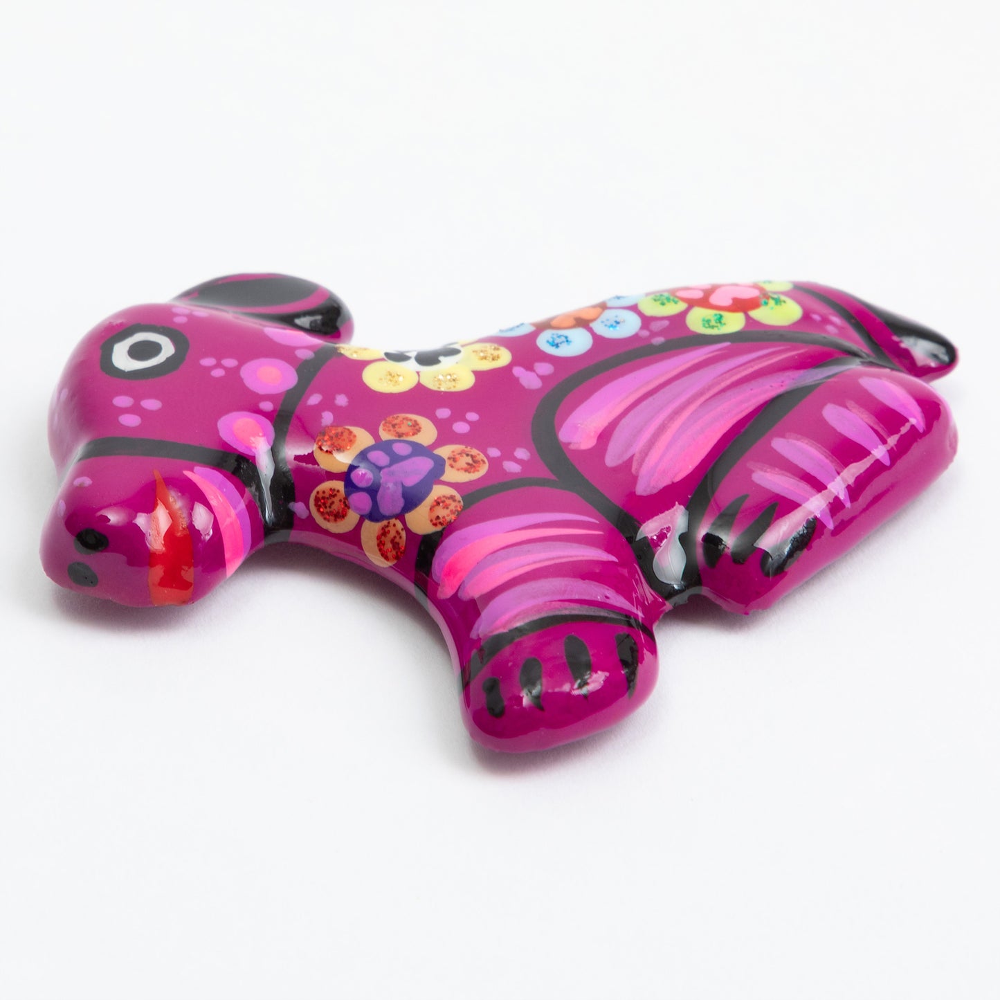 Glossy fuchsia hand painted ceramic dog magnet against a white background.