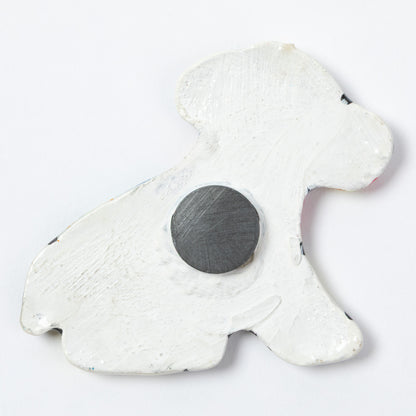 The back of a ceramic dog shaped magnet, against a white background.