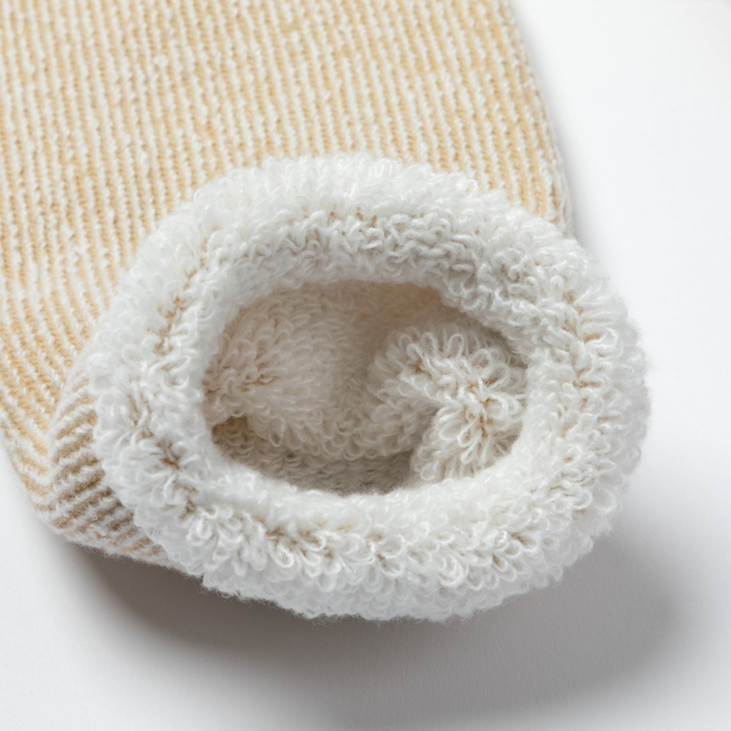 Close-up of a beige and white textured fabric roll on a light background