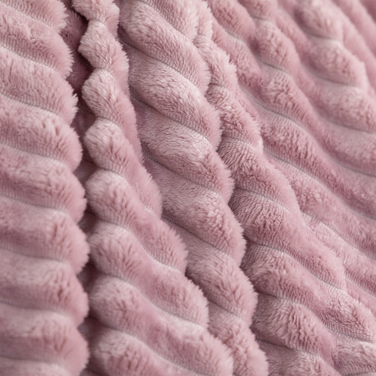 A close-up of a dusty pink textured throw blanket with a ribbed, corduroy-like plush surface.