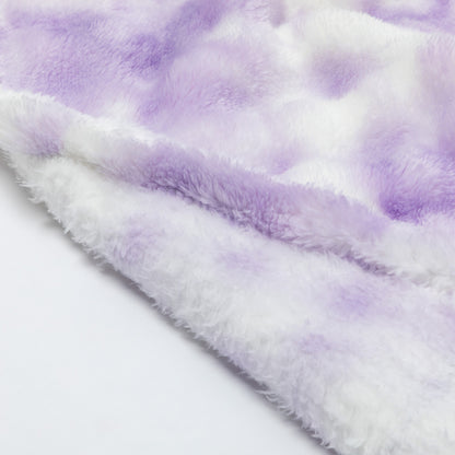 A close-up of a soft, fuzzy plush fabric in a lavender purple and white tie-dye pattern, folded over to show its texture.